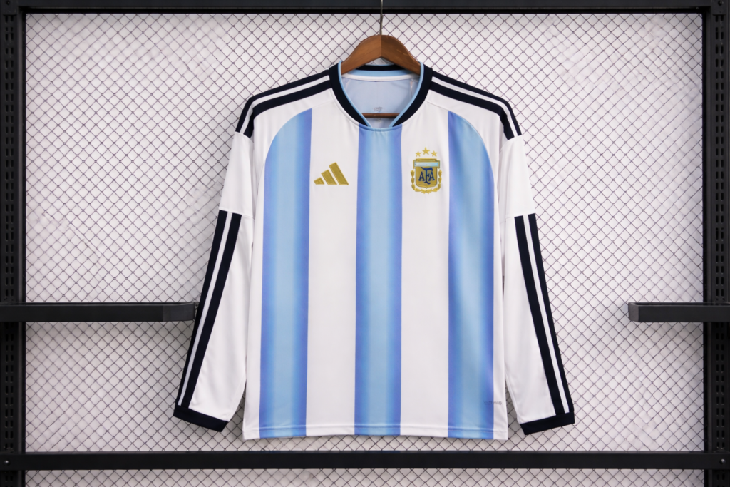 Long-sleeve Argentina soccer shirt featuring national crest and classic striped design displayed on a rack.